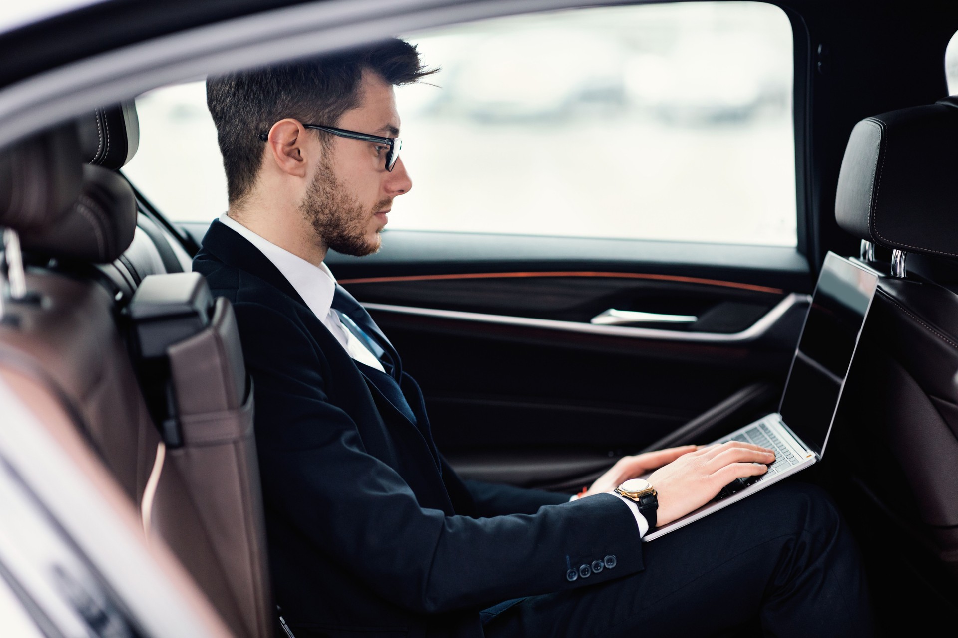 Jovem empresário usando laptop no carro